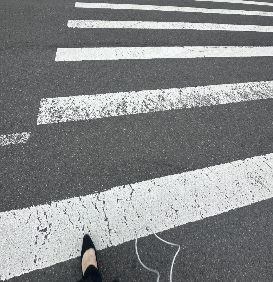 crosswalk from above with one foot visible and earphones on the ground